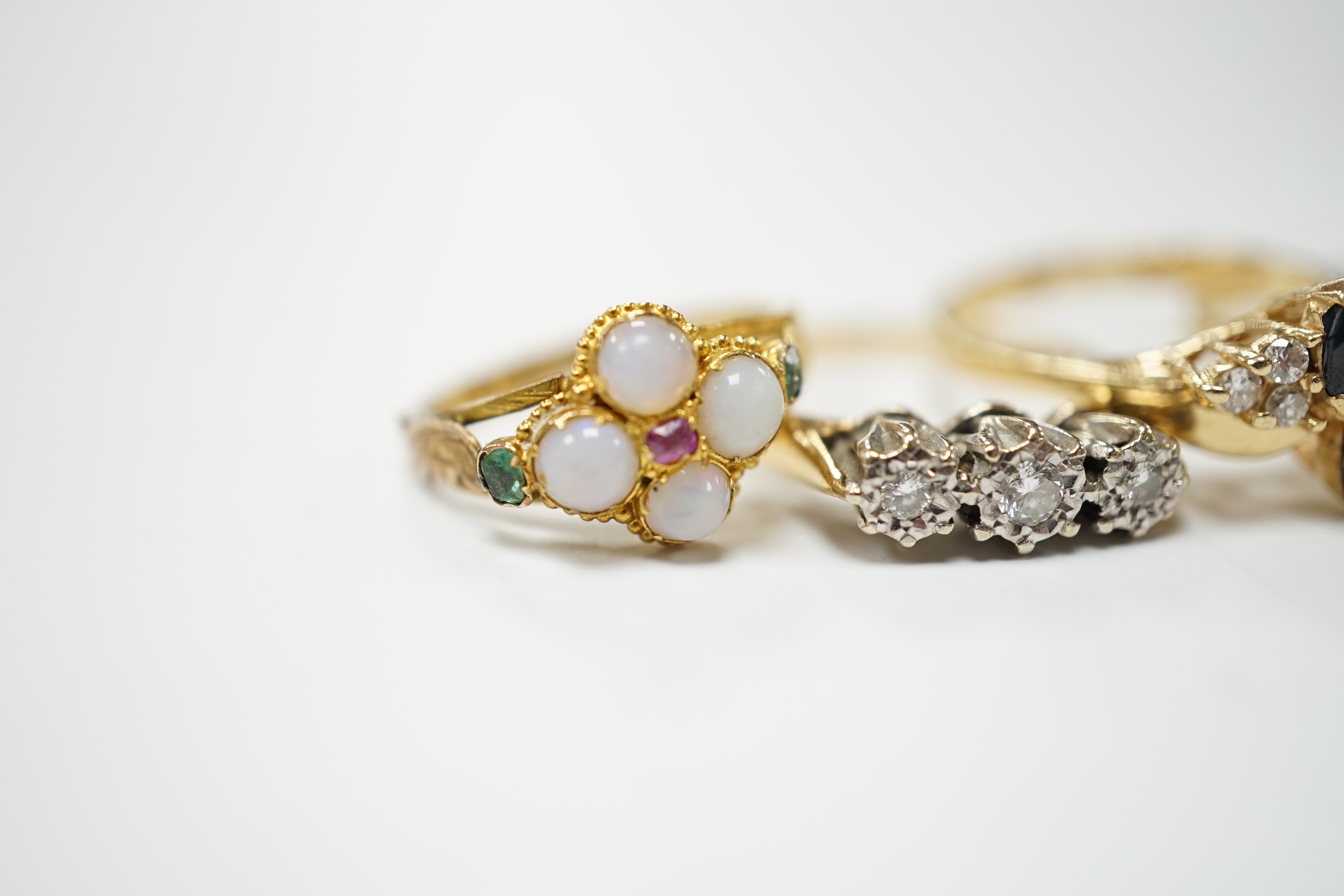 An Edwardian 15ct?, white opal, emerald and amethyst cluster set ring, in the Suffragette colours, size F, together with four other yellow metal and gem set rings including three stone illusion set diamond and a 14k sapp